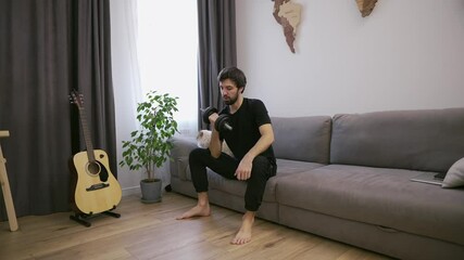 Man doing exercises with dumbbells at home in the living room on the couch