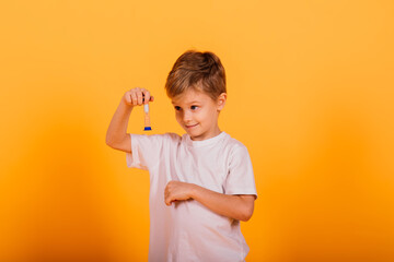 Boy child in a yellow t-shirt on the background in the Studio holding an hourglass