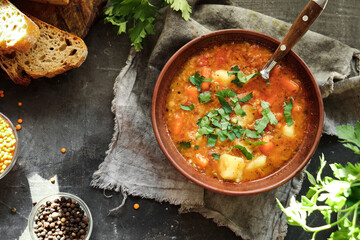 Red lentil soup. Dark background, top view. Traditional spicy soup made from lentils and vegetables. Healthy vegan food