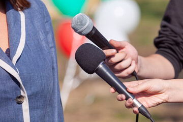 Reporter at news conference holding microphone making media interview with female politician or...