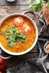 Red lentil soup and ingredients. Wooden background, top view. Traditional spicy soup made from lentils and vegetables. Healthy vegan food