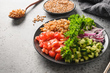 Salad of whole grain cereal spelt with vegetables, tomatoes, cucumbers, greens. Close up.