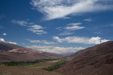 Idyllic valley with a beautiful sky. Panorama view of Humahuaca ravine, brown mountains, Andes desert, green valley and Tilcara village in Jujuy, Argentina.