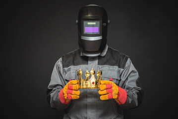 Welder in welding helmet with a golden crown award trophy in the hands. Best welder concept. Royal welding service.