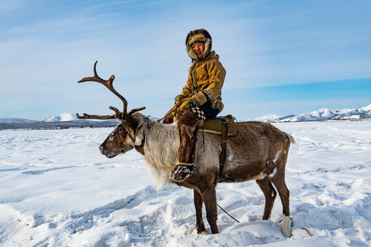 Evenk boy sitting on a reindeer, Oymyakon, Sakha Republic (Yakutia), Russia