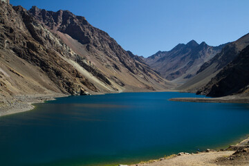 The deep blue color water lake very high in the Andes mountains. View of the Inca Lagoon in Chile,  surrounded by rocky mountains and cliffs. 