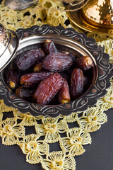 Sweet,dry date fruits in vintage metal bowl on black surface.Ramadan concept.