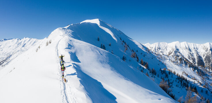 A team of three skiers advances on the mountain ridge, Mount Meriggio, Valtellina, Lombardy