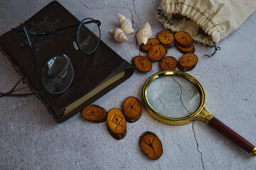 Fototapeta na wymiar on the table are runes, a book ,a magnifying glass