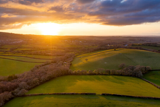 Aerial vista by drone of rolling countryside at sunset in spring, Devon