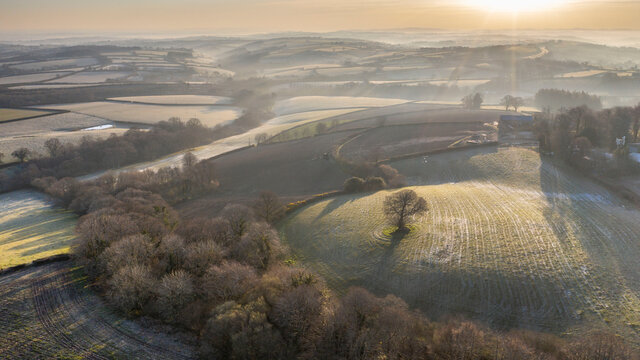 Aerial vista by drone of frosty rolling countryside at dawn in spring, Devon