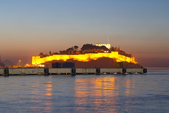 The Byzantine-era fortress, illuminated at dusk, on Guvercin Ada (Pigeon Island), on the Aegean coast, in Kusadasi, Turkey Minor