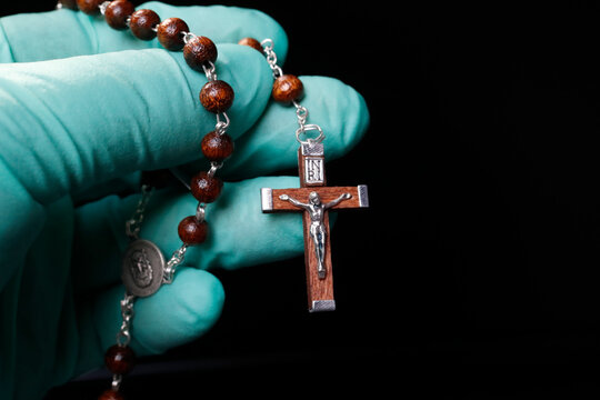Coronavirus (COVID-19) epidemic, Christian praying rosary beads with protecting glove, France