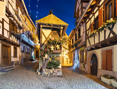 Half-timbered houses along Rue du Rempart Sud lit up with Christmas decorations at night, Eguisheim, Alsace, France