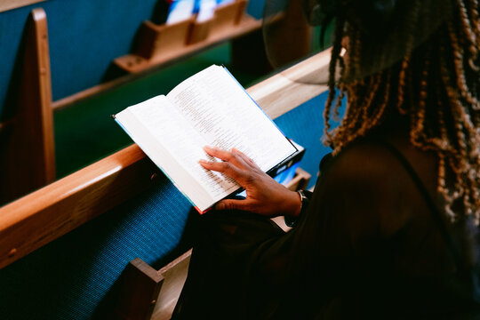 Woman sitting in pews and reading bible at church