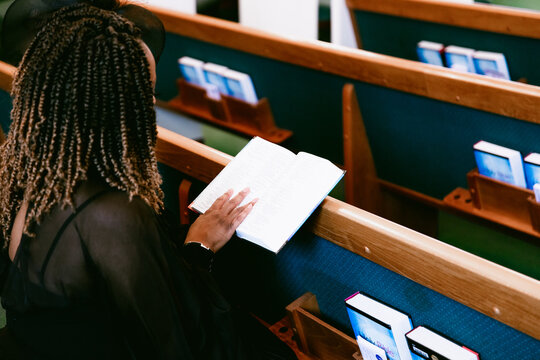 Woman sitting in pews and reading bible at church
