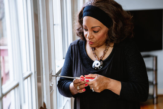 Senior Woman Installing Eco-friendly Light Switch, DIY