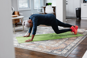 Black senior woman doing mountain climber exercise at home