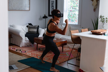 Black woman does boxing exercise at home using virtual reality technology
