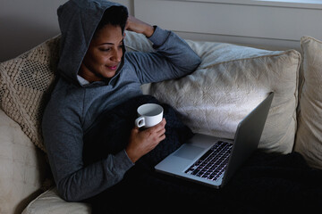 Mature woman snuggled on couch on laptop