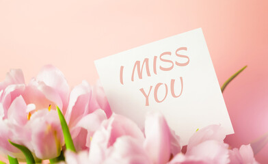 Obraz premium A note with I MISS YOU text hidden in a bunch of pink tulips. Love, romance