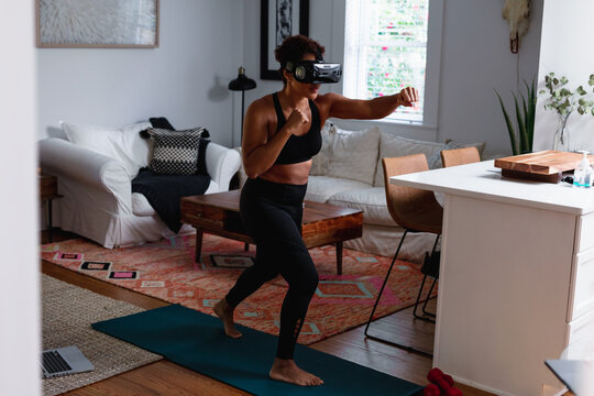 Black woman does boxing exercise at home using virtual reality technology
