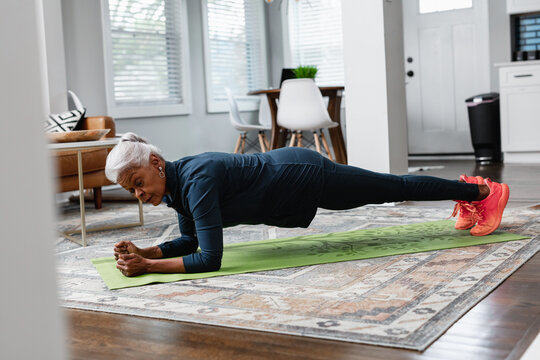 Senior woman working out at home doing planks and pushups