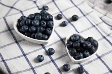 Fresh blueberries in a small heart shaped plates on a checked napkin . Top view. Rustic. Health and vitamins. Love to your body