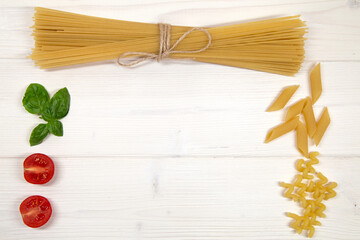 Italian pasta, cherry tomatoes and basil on wooden background