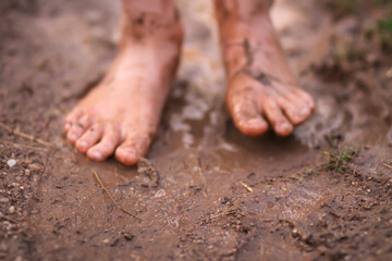 Barefoot girl walks through a puddles of water after the summer rain.