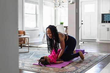 Black mom helps daughter practice yoga exercise together