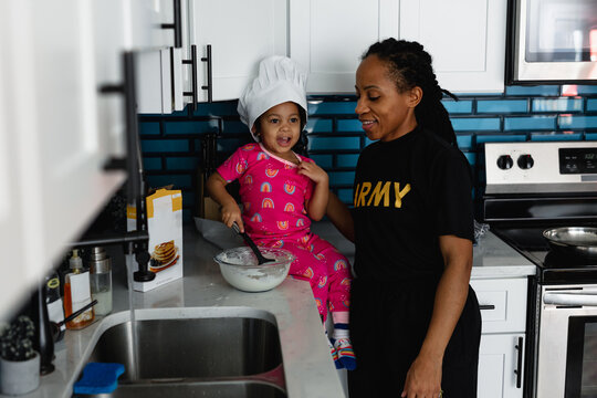 Mother and daughter cook breakfast pancakes in kitchen