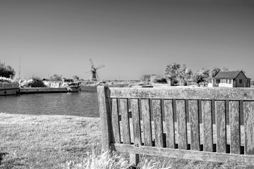 Wooden bench on the  bank of the River Thurne in the Norfolk Broads and countryside. 