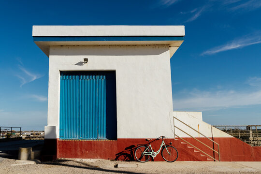 Bicycle leaning on multi colored built structure against sky during sunny day