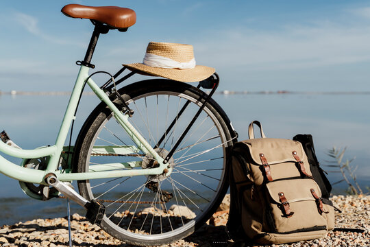 Backpack leaning on bicycle with hat at Ebro Delta against sky on sunny day, Spain