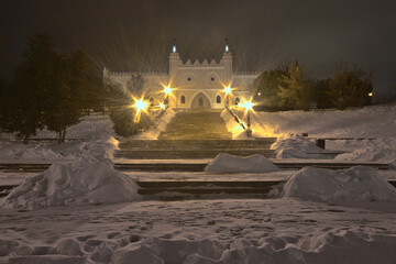 Snow-covered stairs in front of the Lublin Castle illuminated by lanterns