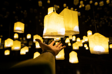 Man presenting illuminated design lamps hanging outdoors at night