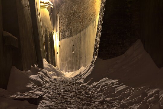 A narrow street covered with snow between tenement houses
