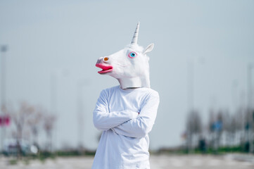 Man wearing unicorn mask posing to camera © OscarStock