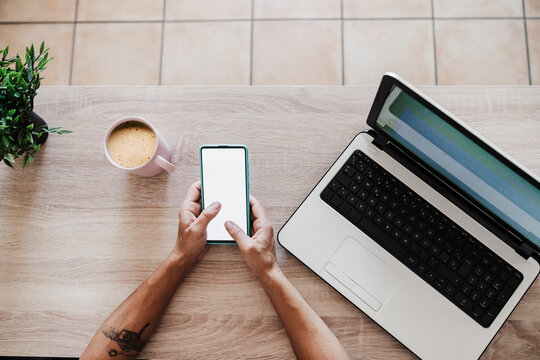 Businesswoman using smart phone amidst laptop and coffee cup at table