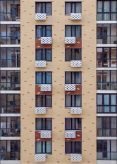 Fototapeta na wymiar Windows and glass balconies on the abstract patterned brick wall