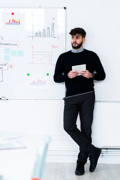 Businessman with digital tablet standing in front of whiteboard in office