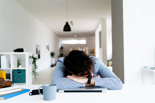 Tired businessman sleeping on laptop in creative office