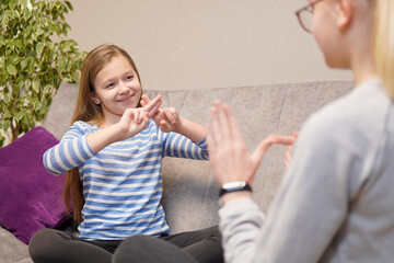 two deaf girls talking gestures on sofa