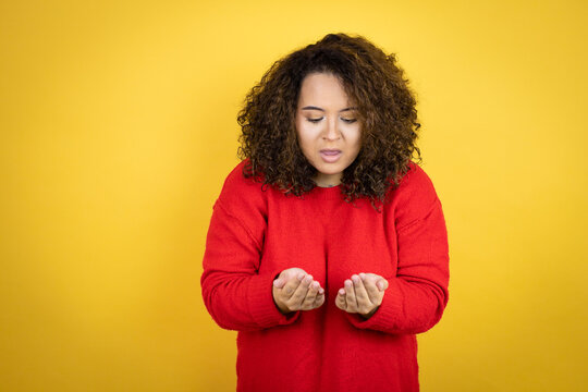 Young African American Woman Wearing Red Sweater Over Yellow Background Smiling With Hands Palms Together Receiving Or Giving Gesture. Hold And Protection