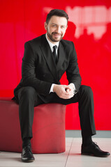 Man in a classic black business suit on a red background