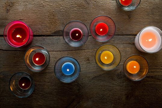 Colorful glass candles burning on wooden surface