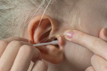 women's ear close-up to clean the cotton bud. deafness concept