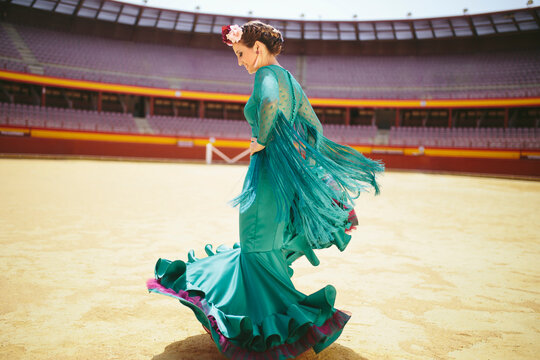 Young woman wearing blue dress flamenco dancing in bullring