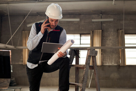 Male engineer talking over mobile phone while using digital tablet in building